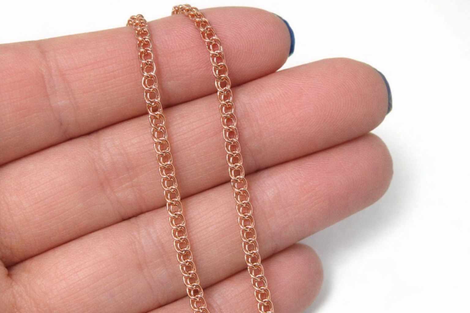 Närbild på ett Bismarckhalsband i roséguld vilande mot fingrar.